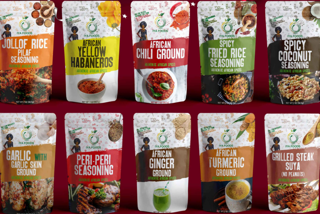 An image showcasing a variety of flavored rice products from Iya Foods, displayed against a vibrant red background. Each package features colorful labels indicating different flavors, including coconut rice, jollof rice, and basmati rice, reflecting the brand's diverse range of culinary offerings.